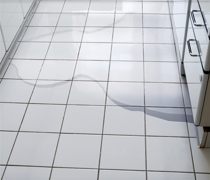 a puddle of water on the white tile floor