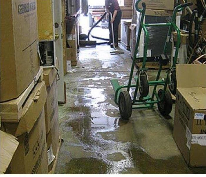 SERVPRO tech removing water from floor of warehouse